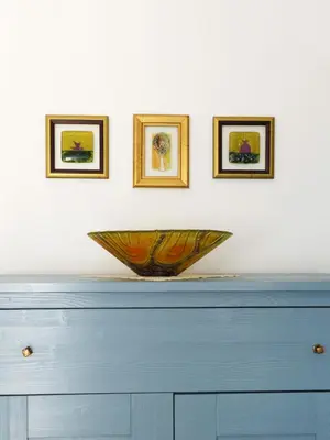a bowl on top of a dresser with three pictures on the wall at Apartment Galerija in Radovljica
