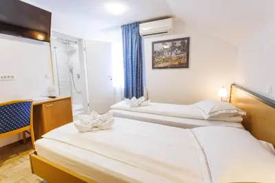 two beds in a hotel room with a window at Hotel Vegov Hram in Dol pri Ljubljani
