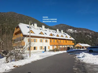 a building in the snow with a mountain in the background at Sunee Apartment in Kranjska Gora
