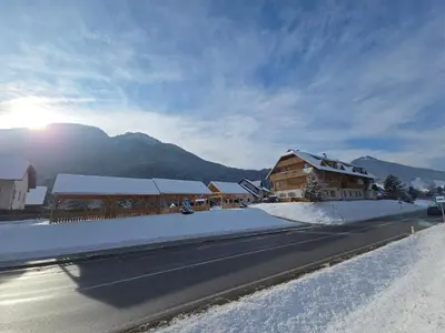 a snow covered street with a house and a mountain at Sunee Apartment in Kranjska Gora