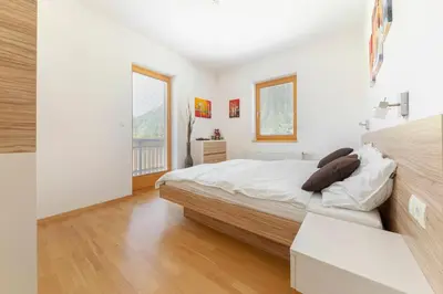 a white bedroom with a bed and a window at Sunee Apartment in Kranjska Gora