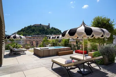 a patio with an umbrella and chairs and a pool at AS Boutique Hotel, superior in Ljubljana