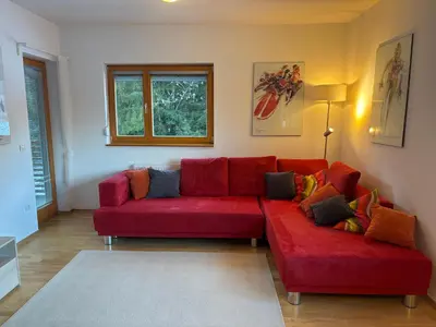 a living room with a red couch and a window at Apartment Lesnina in Kranjska Gora