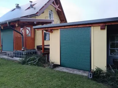 a house with green garage doors on the side of it at Nebesa so tudi na zemlji in Tomaž pri Ormožu