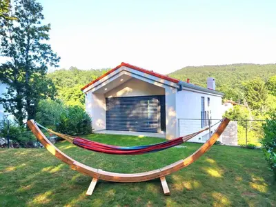 a hammock in the grass in front of a house at Holiday house Sara in Kozina