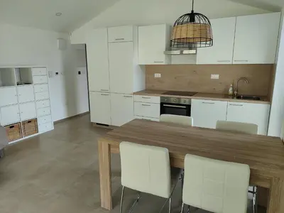 a kitchen with a wooden table and white cabinets at Holiday house Sara in Kozina