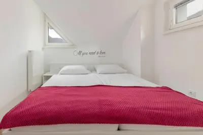 a white bedroom with a red blanket on a bed at Cadys Apartment in Kranjska Gora