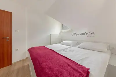 a bedroom with a white bed with a red blanket on it at Cadys Apartment in Kranjska Gora