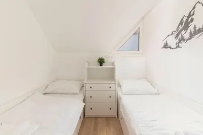 two beds in a room with white walls and a window at Cadys Apartment in Kranjska Gora