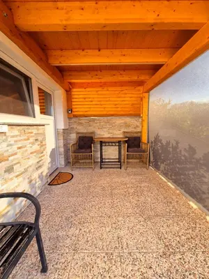 a screened in porch with two chairs and a table at Apartment Teja in Brezovec