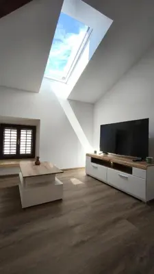 a white living room with a tv and a skylight at New boutique apartments house Gabrijela Mrak in old Tolmin in Tolmin