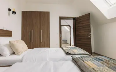a bedroom with a white bed and a wooden cabinet at Hiša na Ravnah in Pišece
