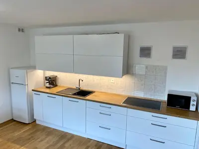 a kitchen with white cabinets and a sink and a refrigerator at Spacious APT in a Quiet Neighbourhood + Private Parking in Ljubljana