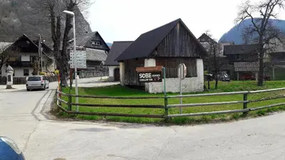a small building with a fence in front of a house at Hostel, Rooms and Apartment Ceklin in Bohinj
