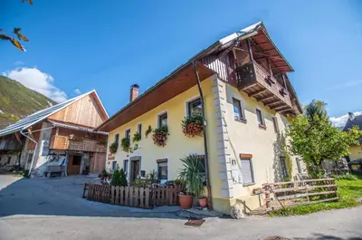 an old house with a wooden fence in front of it at Hostel, Rooms and Apartment Ceklin in Bohinj