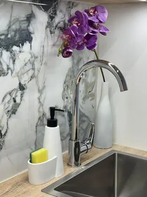 a kitchen sink with a vase of purple flowers and a sink at Studio with a view on City center park in Maribor