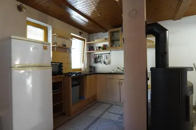 a kitchen with a white refrigerator and wooden cabinets at Koča Kopriva in Križe
