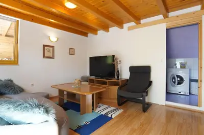 a living room with a television and a chair at Koča Kopriva in Križe