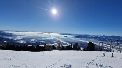 a snow covered mountain with the sun in the sky at Koča Kopriva in Križe