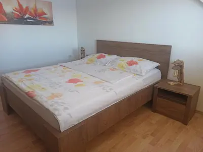 a bedroom with a bed with a wooden headboard at Apartments Skok in Bled