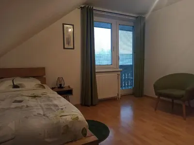 a bedroom with a bed and a chair and a window at Apartments Skok in Bled