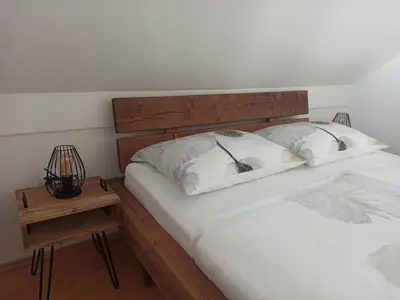 a bed with two white pillows and a night stand at Apartments Skok in Bled