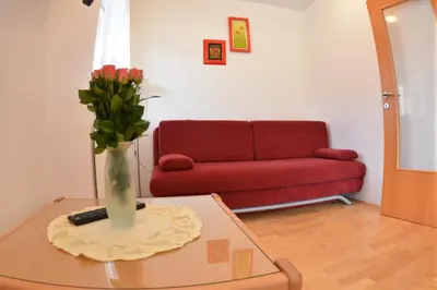 a living room with a couch and a vase of flowers on a table at Apartments Rožič in Kranjska Gora
