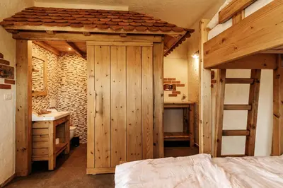 a bedroom with a wooden bed and a bunk bed with a ladder at Gostilnica Orle - Sleeping in the tower in Škofljica