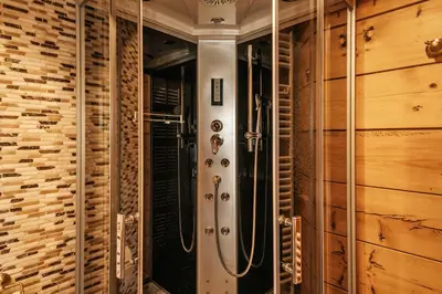 a walk in shower in a room with wooden walls at Gostilnica Orle - Sleeping in the tower in Škofljica