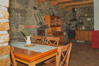 a kitchen with a table and a stone fireplace at Holiday Home GaMaJaMa in Dobravlje