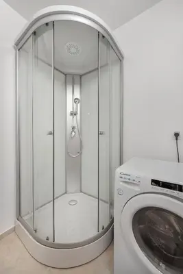 a shower in a bathroom next to a washing machine at SMART APARTMENT LJUBLJANA in Spodnja Šiška