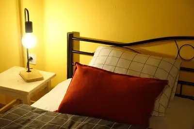 a bedroom with a bed with a red pillow and a lamp at LAAS ART GALLERY in Stari Trg pri Ložu