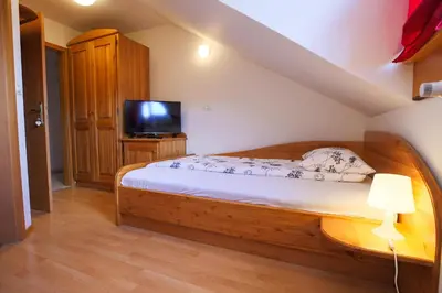 a bedroom with a wooden bed and a television at Domačija Malnarjevi in Villa Slavina