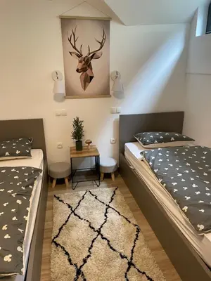 a bedroom with two beds and a table at Apartma Med smrekami Golte in Mozirje