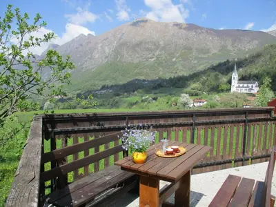 a wooden table on a balcony with a view of a mountain at Holiday Home Krn&Relax in Kobarid