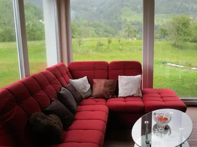 a red couch in a room with a large window at Holiday Home Krn&Relax in Kobarid