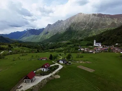 a small village in a green field with mountains at Holiday Home Krn&Relax in Kobarid