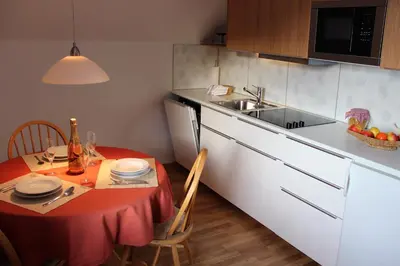 a small kitchen with a table with a red table cloth at Apartments Koblar in Kranjska Gora