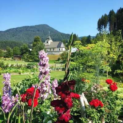 a garden of flowers with a house in the background at Apartments Koblar in Kranjska Gora