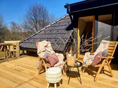 a deck with two chairs and a black building at Koča na samem in Moravske Toplice