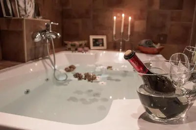a bath tub with a bottle of wine in a glass at Koča na samem in Moravske Toplice