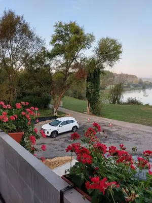 a white car parked in a parking lot with red flowers at Prenočišče ČERNOŠA Apartma Studio in Gradišče v Slovenskih Goricah