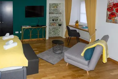 a living room with a bed and a chair at Studio MAYA in Maribor
