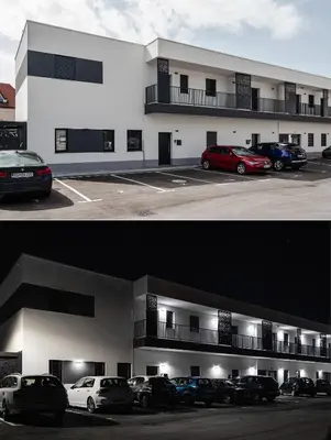 a building with cars parked in a parking lot at Apartma Vila Center LUX in Slovenj Gradec