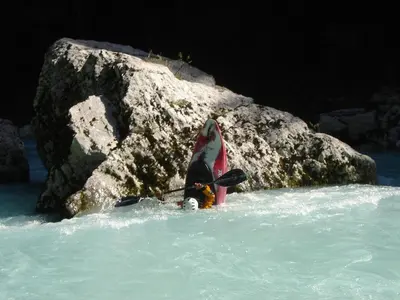 a person standing in the water next to a rock at Apartment Makuc in Bovec