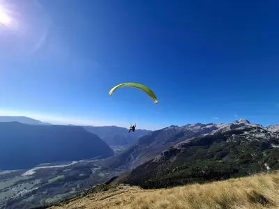 a person flying a parachute over a mountain at Apartment Makuc in Bovec