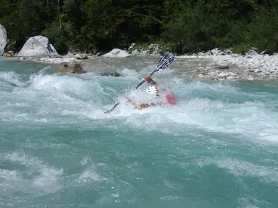 a person in a raft in a river with a paddle at Apartment Makuc in Bovec