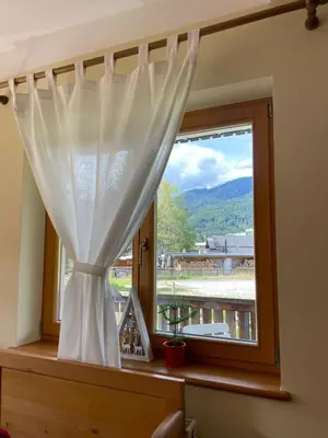 a window with a curtain and a view of a mountain at Apartments Vršič with beautiful views on the Mountains with free parking in Kranjska Gora