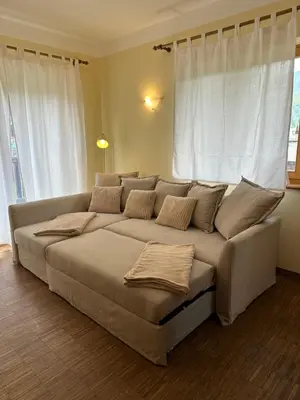 a large couch in a living room with white curtains at Apartments Vršič with beautiful views on the Mountains with free parking in Kranjska Gora