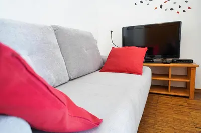 a gray couch with red pillows and a television at Apartments Vršič with beautiful views on the Mountains with free parking in Kranjska Gora